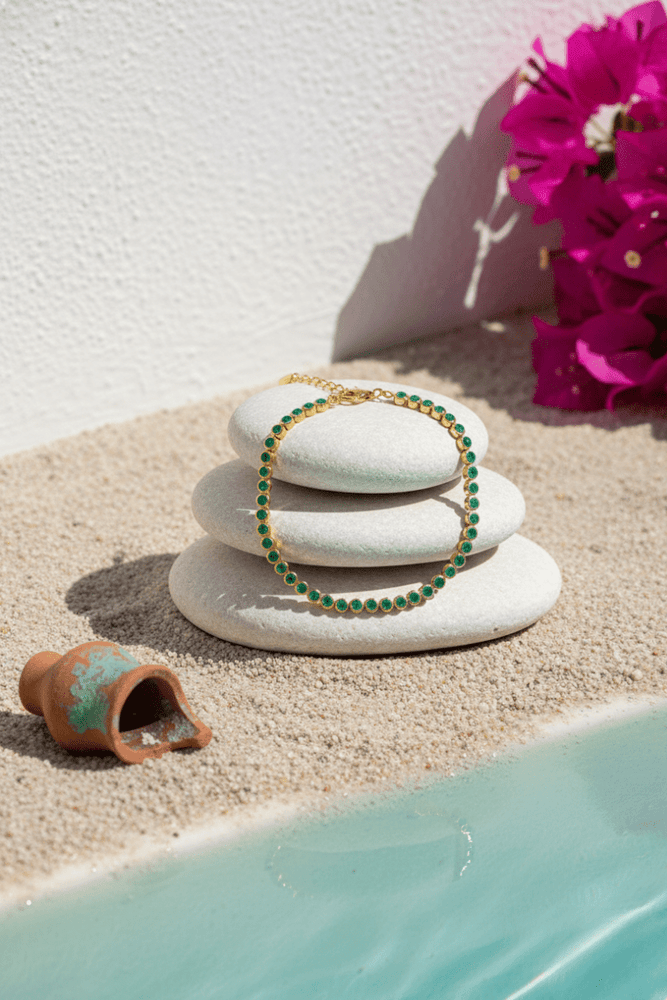 
                  
                    Bracelets on stacked stones with a pink flower and small pot by a pool
                  
                