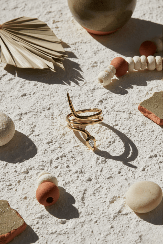 Gold spiral necklace on a textured surface with decorative elements